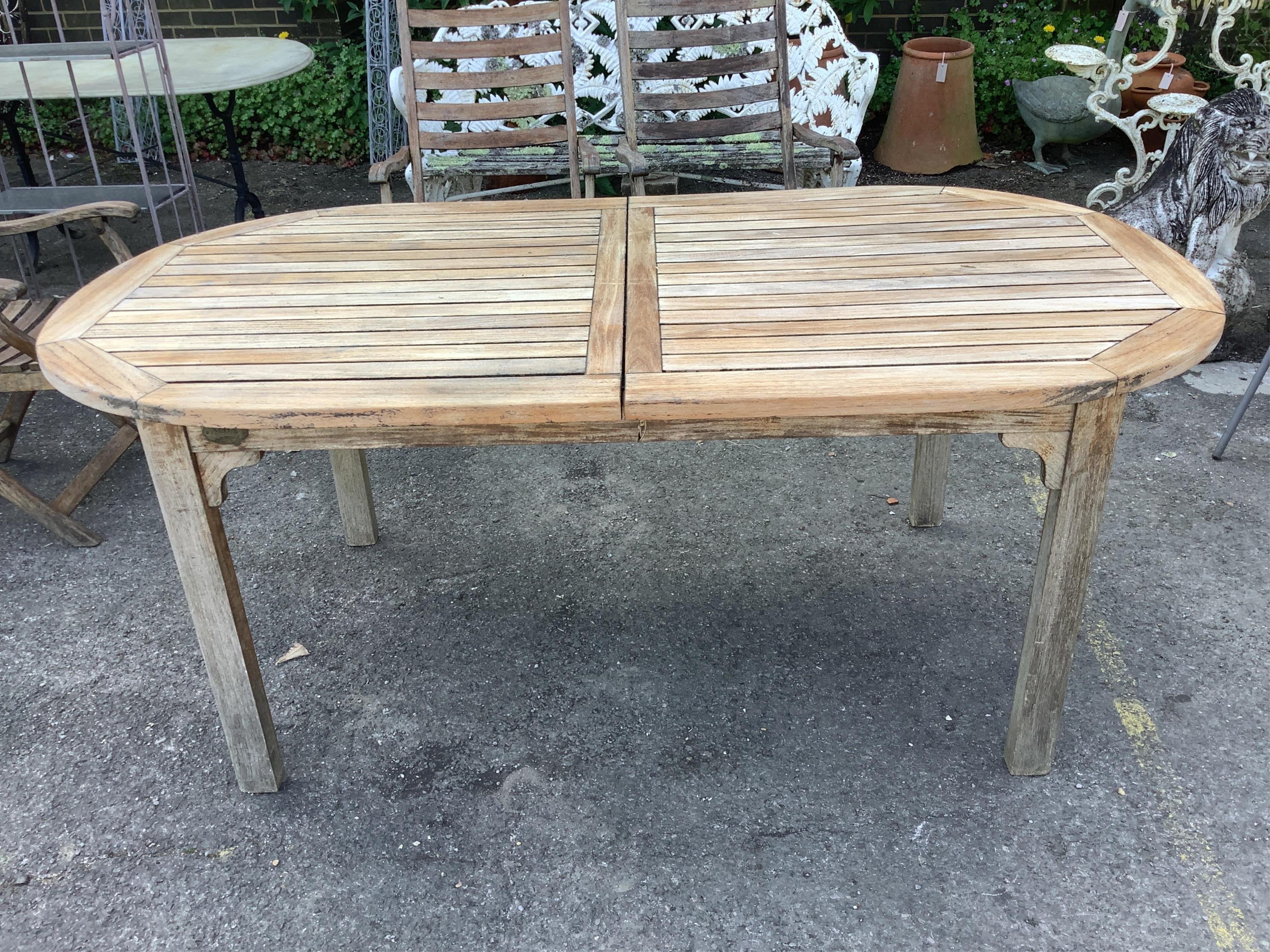A weathered slatted teak Nova extending garden table, width 240cm extended, depth 100cm, height 71cm and six teak Alexander Rose folding chairs